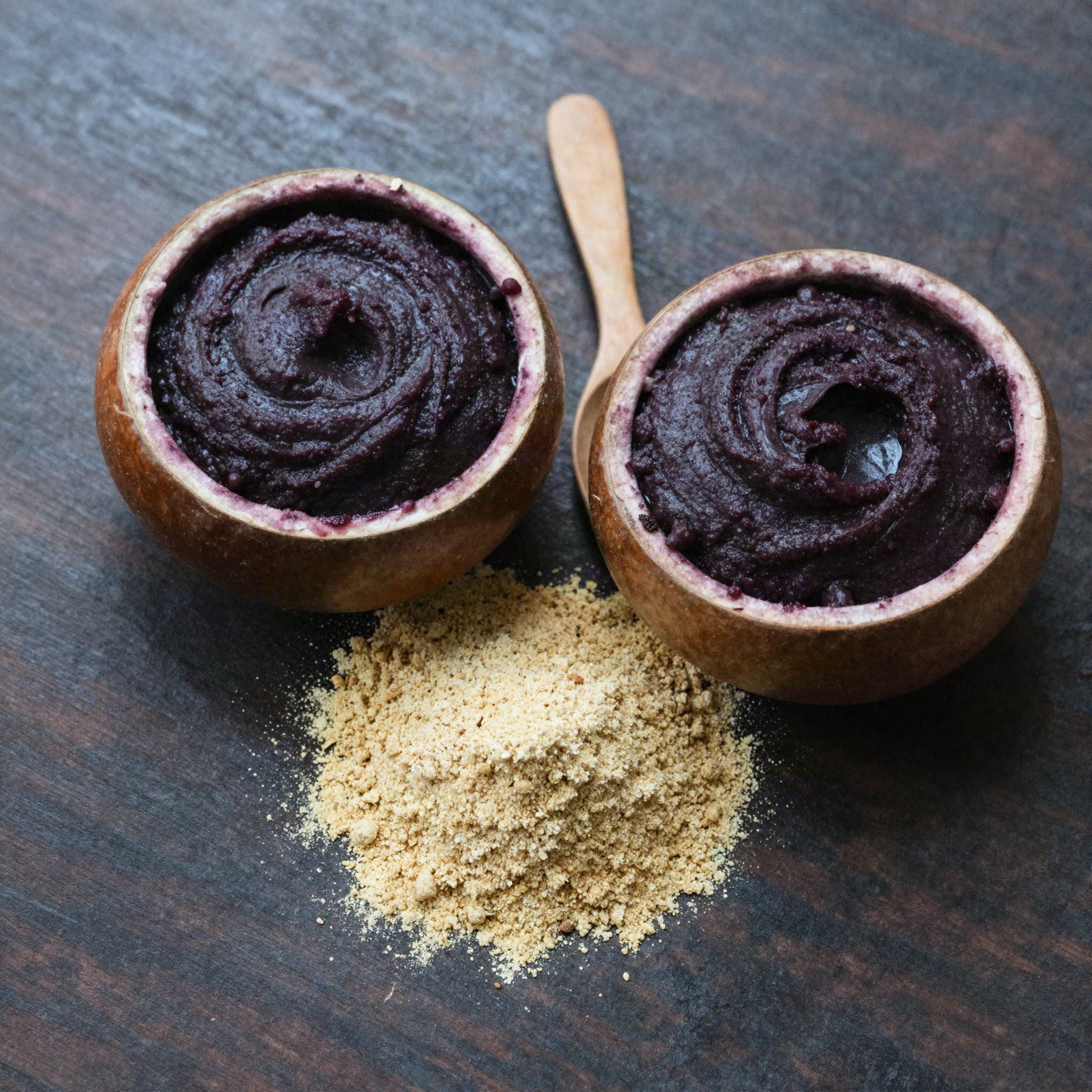Duas cuias de açaí e um montinho de farinha d'água sobre madeira escura